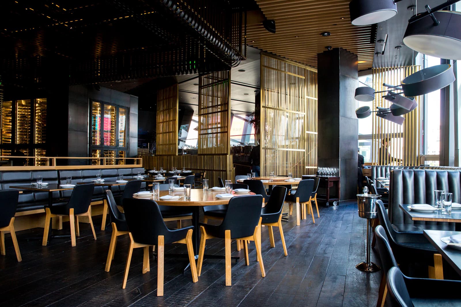 Warmly lit restaurant dining room with timber tables, pendant lighting and a service counter