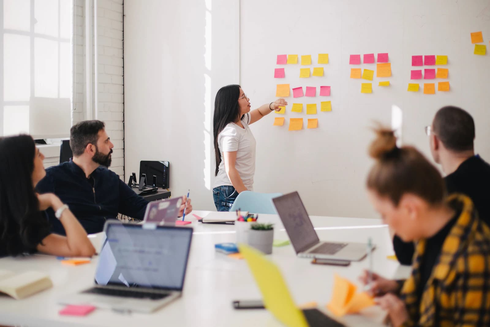 Trainer leading a hospitality workshop beside a whiteboard of sticky notes